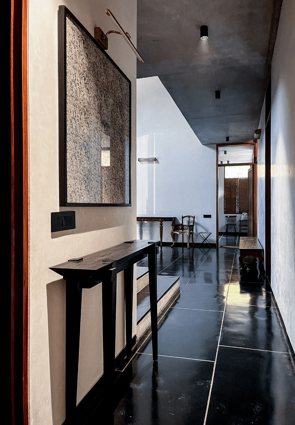 Circulation corridor — polished black stone floor, gallery-hung artwork, track lighting