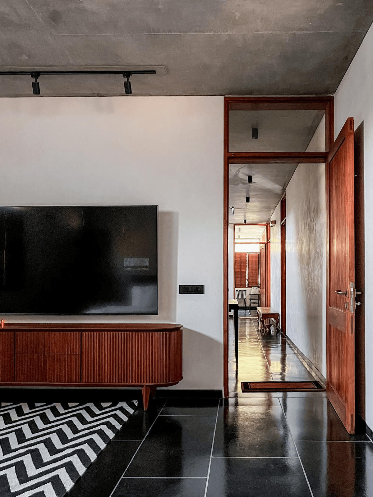 Media room — fluted teak sideboard, chevron rug, teak door frames with transom glass