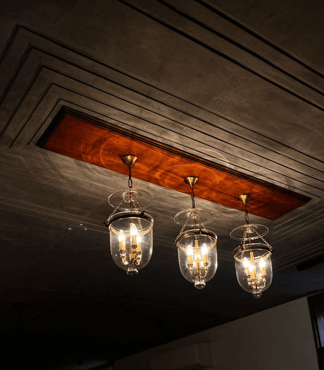 Dining pendant detail — Victorian bell-jar lanterns in brass, teak ceiling coffer reveal