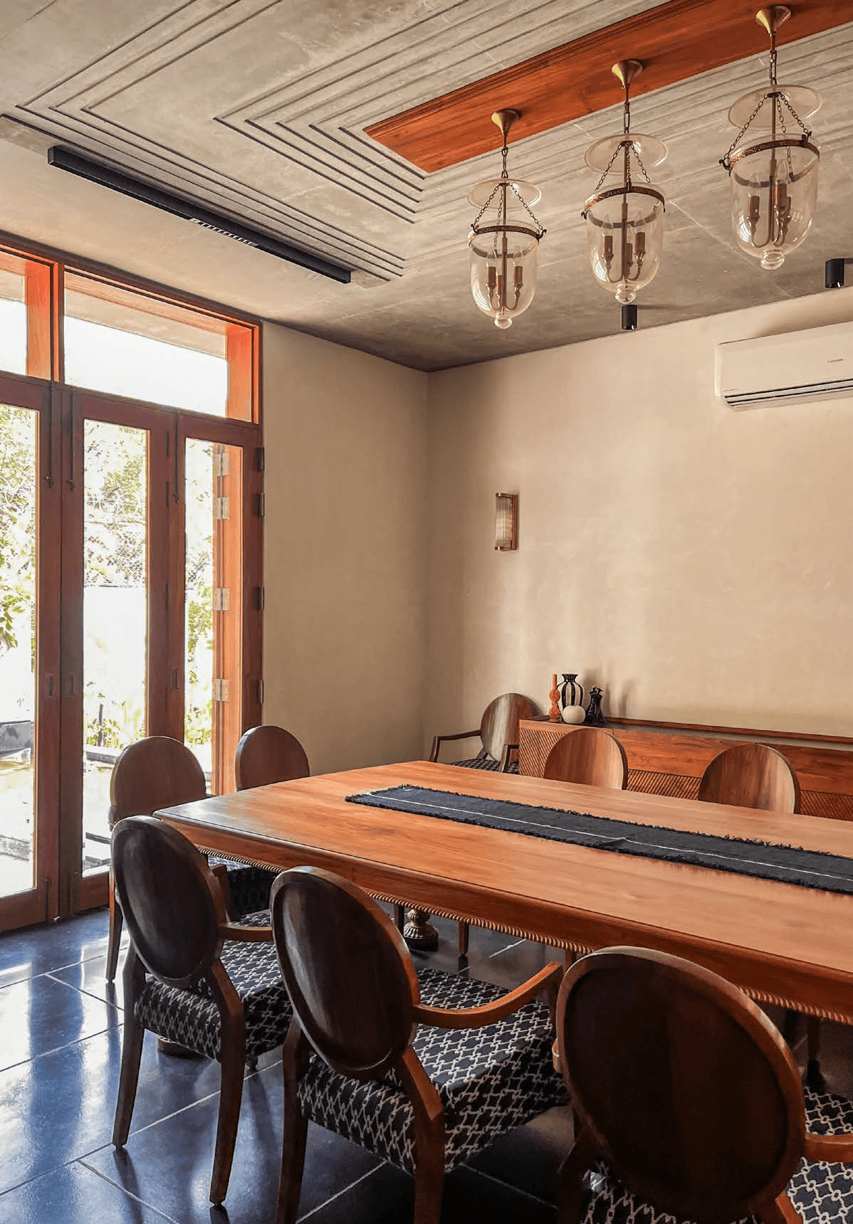 Dining room — teak table, Victorian barrel chairs, brass bell-jar pendants, teak ceiling coffer